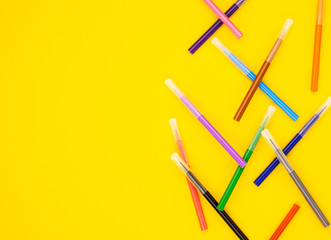 colorful markers are scattered on a yellow background. educational school supplies