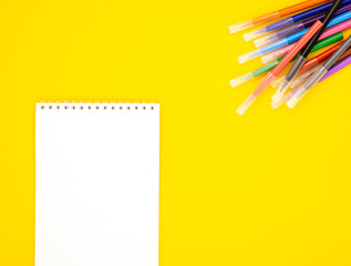 white blank Notepad with markers on a yellow background, space for text