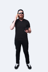 Full length photo of man with beard talking on phone and holding coffee