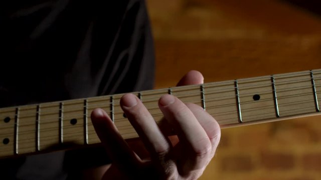 Guitar player practices technique exercise on electric guitar, closeup on neck