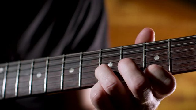 Guitarist practices sweep picking pattern on electric guitar, closeup on neck.