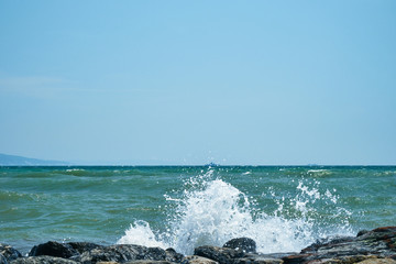 Image of the sea shore. In the background is a warship.
