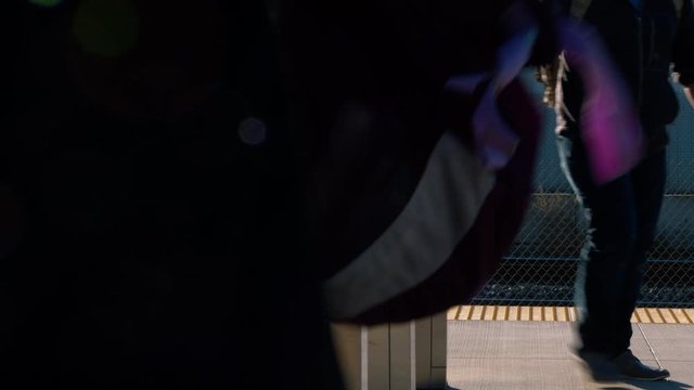 People scanning their badges for a commuter train.  Finishing a days work.  Walking to the station and waiting for the train to arrive.