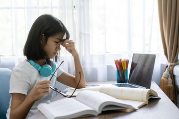 Asian girl eye strain tension or blurry vision problem, Studying homework online lesson at home,...