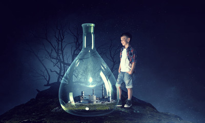 Boy holding glass flask with landscape inside it