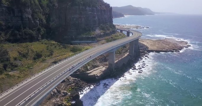 Drone rising over the spectacular Sea Cliff Bridge, cliffs and ocean