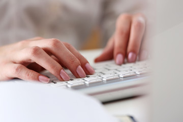 Female hands typing on silver keyboard using computer pc