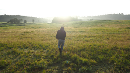 A man standing facing the sun Looking at the wide field, heart-shaped hand-made, the light of the sun shining through the model.