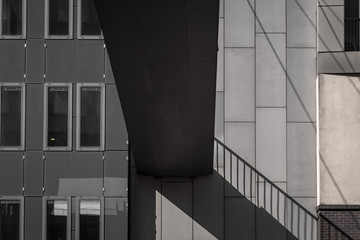 Obraz premium Fußgängerbrücke mit Schatten des Geländers vor einem modernen grauen Gebäude