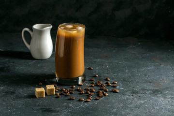 Ice coffee frappe in tall glass. Cool summer drink on a dark background in low key. A stream of...