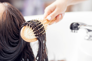 Master applies conditioner to hair using massage comb. Shampooing with special deep cleansing in beauty salon - obrazy, fototapety, plakaty