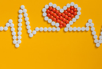 ..Pills in shape of cardiogram and heart pulse on yellow  background. Pharmaceutical and cardiology concept.