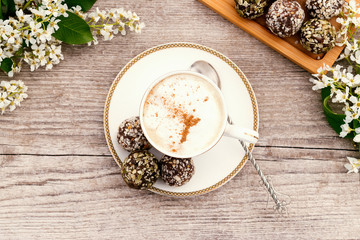 Сup of coffee and protein homemade sweets made from boiled lentils,cocoa powder, peanut paste, dates and decorated with nuts on a wooden background.Сoncept of healthy food and healthy desserts.