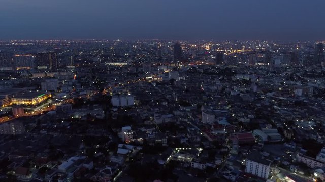 Aerial shot of buildings in residential district against sky, drone flying forward over cityscape at night - Bangkok, Thailand