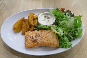 Grilled salmon garnished, roasted salmon steak, with cooked potatoes and sauce on white plate. Food concept.
