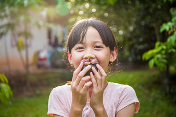Fresh mangosteen in Thai girl's hands, she enjoy eating with her fruit.