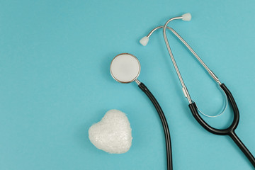 White heart and medical stethoscope on blue background. Concept of cardiology. World Heart Day.