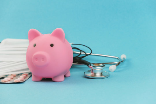 Medical Masks, Stethoscope And Piggy Bank On Blue Background, Medicine Bills And Payments.