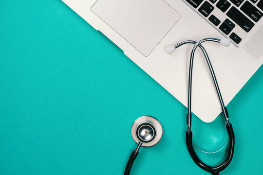 Medical stethoscope and laptop on green background. Concept of medicine online, bills, medical insurance.