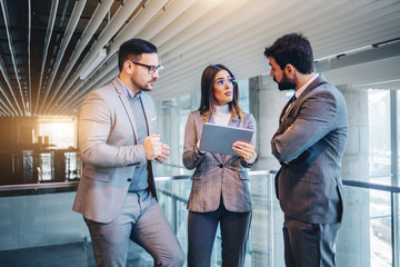 Successful group of real estate agents standing in building in construction process and talking about the best way to sell it. Woman in the middle holding tablet.