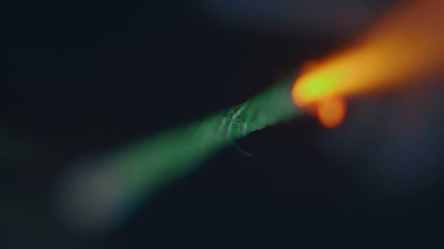A bright stream of fire, sparks and smoke from a lit wick, which is supposed to detonate a bomb or pyrotechnics at a holiday, on a black background. Macro. Closeup. Shallow depth of field. Slow motion