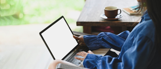 Photo of beautiful woman typing on white blank screen computer laptop that putting on her lap and...