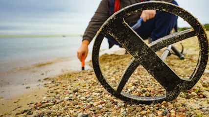Man with metal detector on sea beach