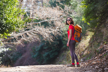 A girl with a backpack goes along a mountain trail.