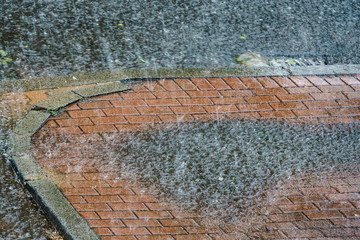 Heavy rain drops falling on city street.