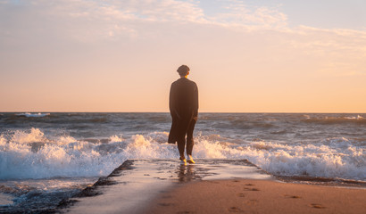 Fototapeta na wymiar 日本 神奈川県 鎌倉の七里ヶ浜の砂浜を夕方に歩く若い日本人男性と美しい夕陽