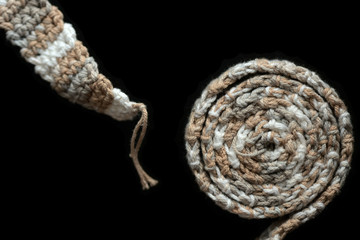 Crochet tape melange yarn rolled up on a black background close up. Top view. Handmade concept