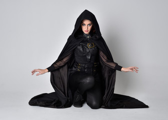 Fantasy portrait of a woman with red hair wearing dark leather assassin costume with long black...