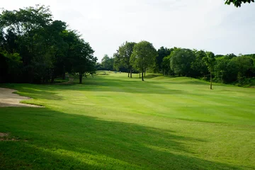 Papier peint photo  Beautiful golf course in a sunny day. Background evening golf course has sunlight shining down. Golf course in the countryside.  © somchai