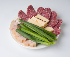 Meat Assarti. Sausage, lard, cheese and green onions on a plate. Cutting
