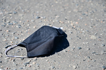 Photo of a protective black mask lying on the pavement during a virus outbreak