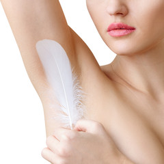 Woman holds white feather near clean armpit. Depilation concept.