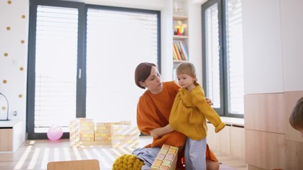 Mother with small children in bedroom in the morning at home, getting dressed.