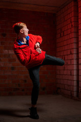 Handsome brunette young male teenager in sweatshirt or hoodie training in dark room with brick...