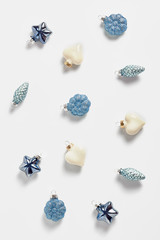 the pattern of Christmas decor on a white background. toys in the form of stars, cones, and hearts of blue color. vertical frame, flat lay, top view