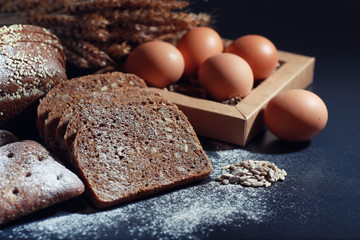 Fresh loaves of bread with wheat and gluten on a black table. Bakery and grocery concept. Fresh,...