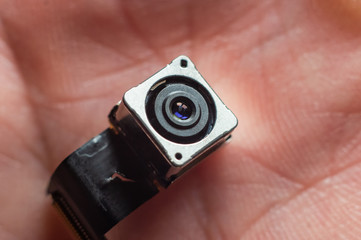 Small camera module on the palm of a hand. Lens close up.