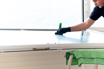 professional cleaneer using a diamond blade scraper to clean a window