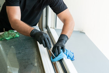 profesional cleaner cleaning a dirty window frame with a micro fiber cloth