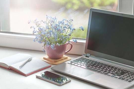 Workplace near the window with computer. Copy space. Modern laptop on desk near window at home. Morning time with warm light. working desk with a cup of coffee. business concept.