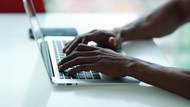 Close-up hands typing on computer laptop, african black man working from home