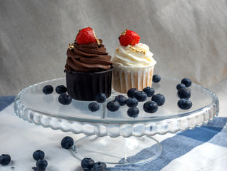 two cream cakes with strawberries and potal on a stand