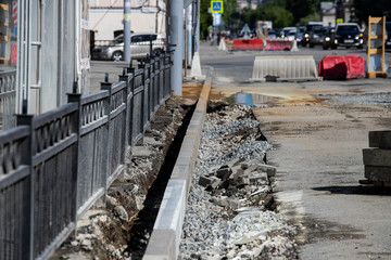 Fototapeta premium Setting road border before laying asphalt. Reconstruction of the sidewalk and replacement of old curbs. Road infrastructure repair