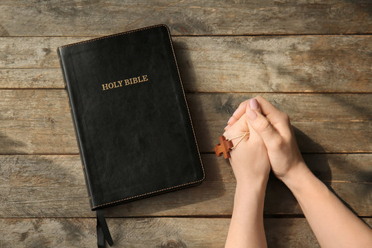 Holy Bible on table of praying woman