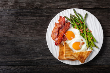 fried eggs, bacon, toast, asparagus on a plate