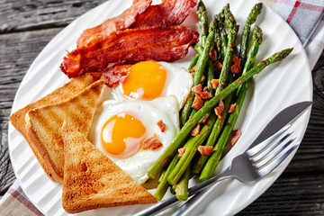 a portion of fried eggs, bacon, toasts, asparagus
